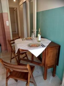 una mesa con mantel blanco y una botella de vino en Cozy apartment for piano lovers in Corfu Town en Corfú