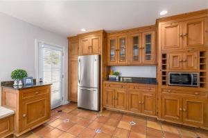 a kitchen with wooden cabinets and a stainless steel refrigerator at Quite Spacious, Hot Tub Near Montecito, EV Charger in Santa Barbara