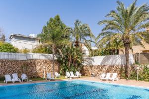 een zwembad met stoelen en palmbomen bij Skyline 1BR Apartment with City and Sea View by Sea N' Rent in Herzelia 