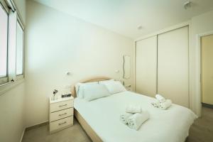 een slaapkamer met een wit bed en handdoeken bij Skyline 1BR Apartment with City and Sea View by Sea N' Rent in Herzelia 