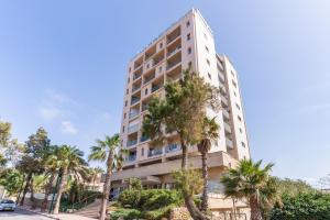 een hoog gebouw met palmbomen ervoor bij Skyline 1BR Apartment with City and Sea View by Sea N' Rent in Herzelia 
