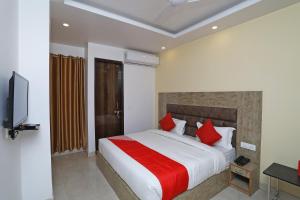 a bedroom with a large bed with red pillows at Hotel O Royal Stay in New Delhi