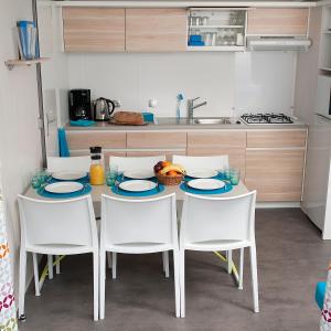 una cocina con una mesa con sillas blancas y una barra en Happy Lodge, en Alphen