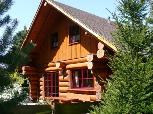 Una cabaña de troncos con una ventana roja y árboles. en Cozy wooden house in Waltershausen near the forest, en Emsetal