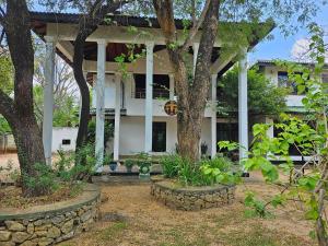 une maison blanche avec des arbres devant elle dans l'établissement Hotel Lihini Village Dambulla, à Dambulla
