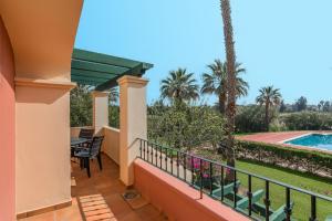 a balcony with a table and chairs and a swimming pool at Hoyo I by Ĥ - Isla Canela Golf GHHI16IA3P78 in Isla Canela