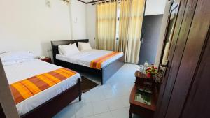 a hotel room with two beds and a window at Hotel Lihini Village Dambulla in Dambulla