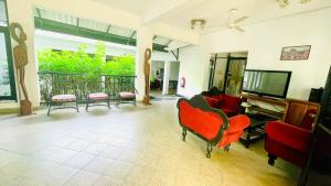a living room with red chairs and a flat screen tv at Hotel Lihini Village Dambulla in Dambulla