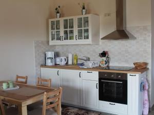 cocina con armarios blancos, mesa y fogones en Modern Holiday Home in Brusow with Roofed Terrace, en Kröpelin