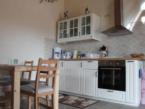 kuchnia z białymi szafkami i stołem z krzesłami w obiekcie Modern Holiday Home in Brusow with Roofed Terrace w mieście Kröpelin