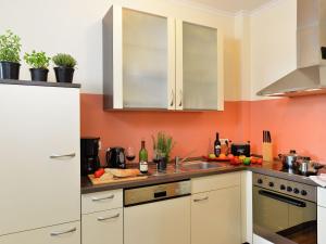 uma cozinha com paredes cor de laranja e armários brancos em Lovely Apartment in M rz with Garden Balcony em Lahr