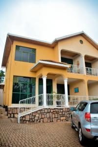 uma casa amarela com um carro estacionado em frente em Tranquil Retreat em Kigali