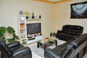 uma sala de estar com 2 cadeiras de couro e uma televisão de ecrã plano em Tranquil Retreat em Kigali