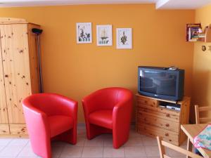 2 sillas rojas y TV en una habitación en Comfortable Apartment near Seabeach in Rerik, en Rerik
