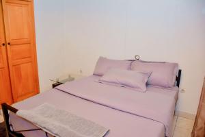 uma cama branca com almofadas roxas num quarto em Tranquil Retreat em Kigali
