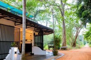 a house in the woods with a bench and trees at Sharta Yala in Tissamaharama