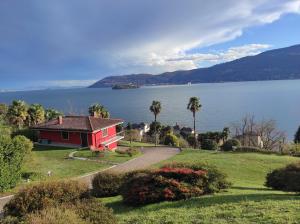 una casa roja en una colina junto a un lago en Villetta Primavera Suna Vista lago CIR10307200215 en Verbania