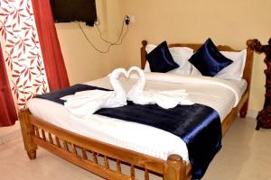 dos cisnes blancos sentados sobre una cama en OYO Home Inn Of Dreams Homestay, en Wayanad