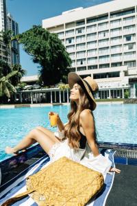 uma mulher de chapéu sentada ao lado de uma piscina em Cinnamon Grand Colombo em Colombo