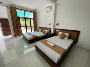 a bedroom with two beds and a large window at Sharta Yala in Tissamaharama