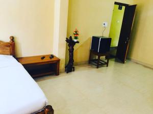 1 dormitorio con 1 cama y TV. en OYO Home Inn Of Dreams Homestay, en Wayanad