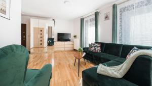 un salon avec un canapé vert et une télévision dans l'établissement Apartamenty Sun & Snow Angel City, à Cracovie