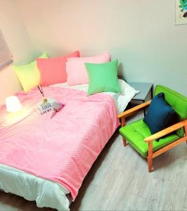 a bedroom with a bed with colorful pillows and a chair at 하이스테이원당53 in Koyang