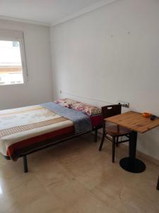 1 dormitorio con cama y mesa de madera en HOLIDAY CENTRE DELUXE, en Alicante