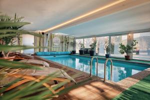 a large swimming pool in a house with a large window at Hotel Hirschenstein in Achslach