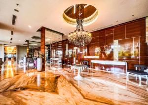 a lobby with a chandelier and tables and chairs at Exquisite 3BR Surabaya Apartment at Via Tower Ciputra World by Le Ciel Hospitality in Surabaya