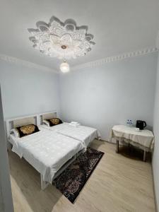 Habitación blanca con 2 camas y lámpara de araña. en Boulevard Architectural Hotel en Bukhara