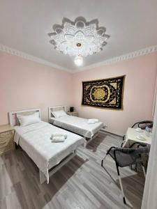 2 Betten in einem Zimmer mit Kronleuchter in der Unterkunft Boulevard Architectural Hotel Wifi 100 MBS in Buxoro