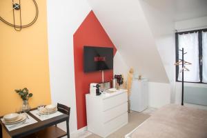 a living room with a tv on a red wall at Le Velvet proche aéroport CDG I Paris I Astérix in Moussy-le-Vieux