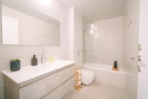 a white bathroom with a sink and a toilet at Lapin Luxury Hotels By Nimizz in Tel Aviv