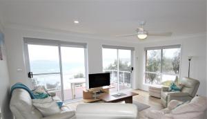 Una sala de estar con muebles blancos y grandes ventanales. en Bellevue, en Manyana