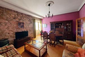sala de estar con mesa y pared de piedra en La Casa de Ana en Fisterra, en Finisterre