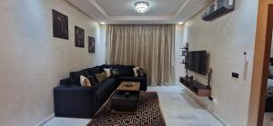 un salon avec un canapé bleu et une télévision dans l'établissement Millénium vip parc appartement, à Mohammedia