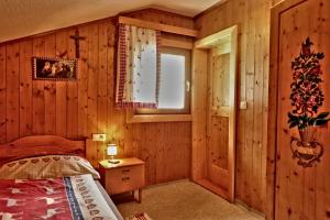 1 dormitorio con paredes de madera, 1 cama y ventana en Almchalet Goldbergleiten, en Großkirchheim