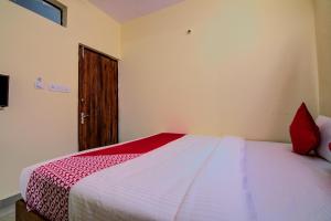um quarto com uma cama com um cobertor vermelho e branco em Flagship Shakthi Nagar em Yelahanka