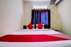 um quarto com uma cama grande e almofadas vermelhas em Flagship Shakthi Nagar em Yelahanka