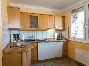 una cocina con armarios de madera y electrodomésticos blancos en Large apartment in the beautiful Sauerland with garden patio and sauna, en Erndtebrück
