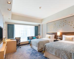 コロンボにあるシナモン グランド コロンボのベッド2台とテレビが備わるホテルルームです。