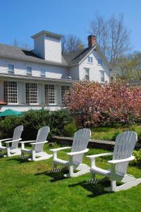 three white chairs sitting in the grass in front of a house at Deerfield Inn in Deerfield
