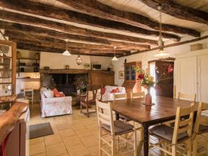 a kitchen and living room with a wooden table and chairs at Farmhouse with private pool large garden and playground in Thenon