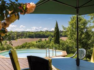 a table with an umbrella next to a swimming pool at Farmhouse with private pool large garden and playground in Thenon