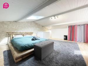 1 dormitorio con 1 cama y 1 reposapiés en una habitación en Le Paul by iZiLi - Centre Ville - Gare, en Niort