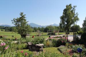 a garden with flowers and a playground in the background at Stefanutti-Hof in Grabenstätt