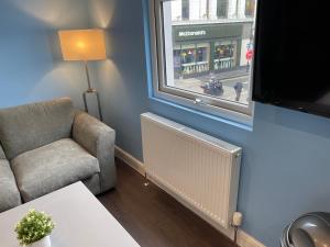a living room with a couch and a chair and a window at Luxurious Restful Studio Flat, Less Than 30 Mins From Centre! in London