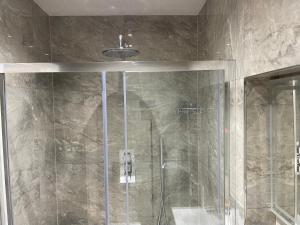 baño con ducha y puerta de cristal en Luxurious Restful Studio Flat, Less Than 30 Mins From Centre! en Londres