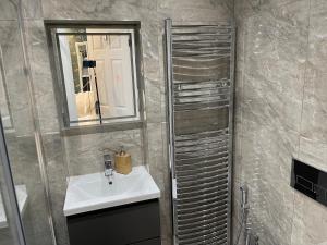ein Badezimmer mit Waschbecken und Spiegel in der Unterkunft Luxurious Restful Studio Flat, Less Than 30 Mins From Centre! in London